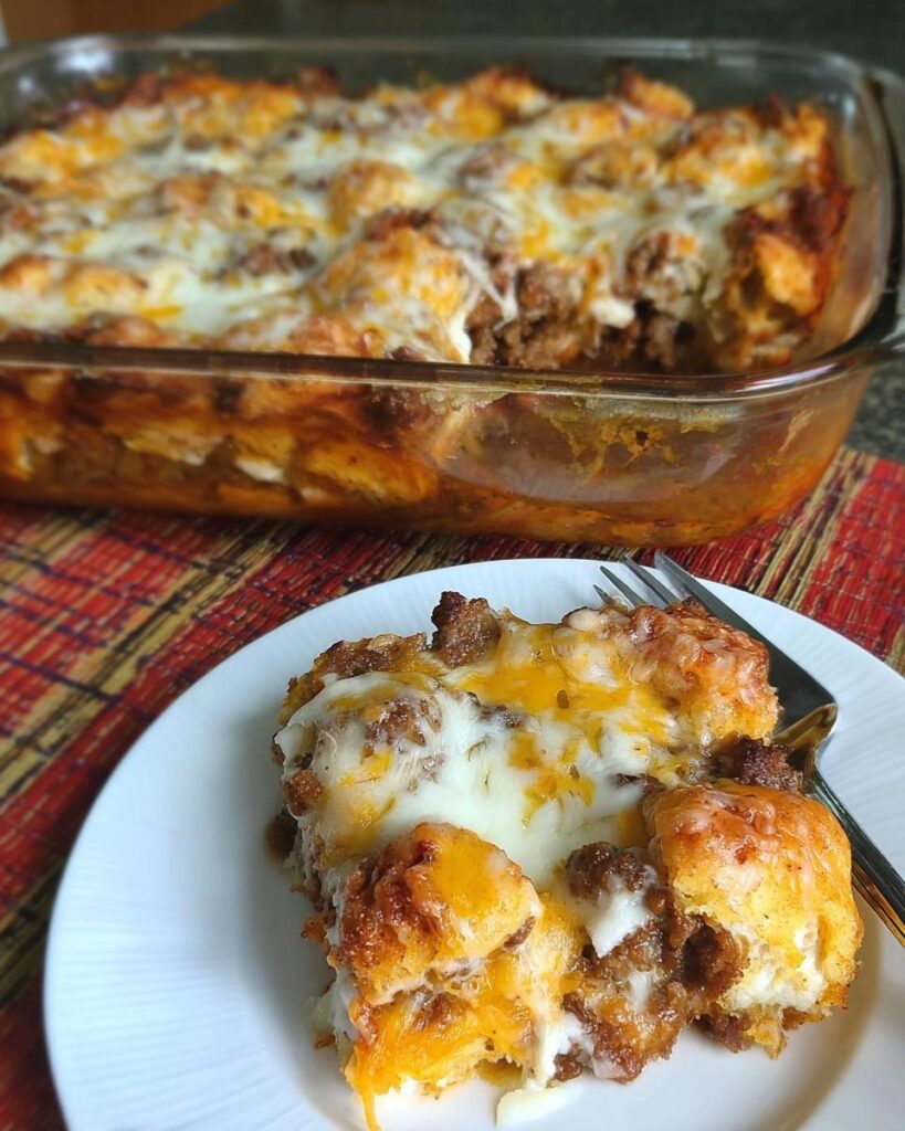 A serving of Sausage Pizza Casserole on a white plate, topped with melted mozzarella and cheddar cheese.