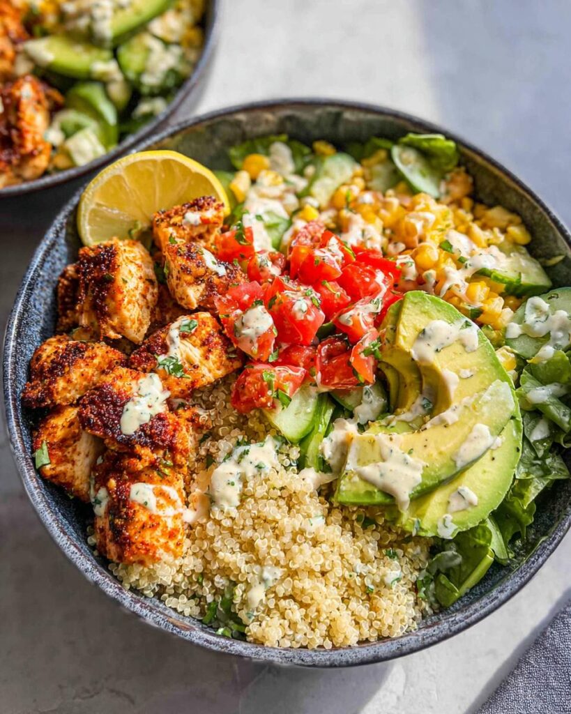Nahaufnahme einer Gesunde Dinner Bowl mit gewürztem Hähnchen, Quinoa, Avocado, Tomaten und Dressing.
