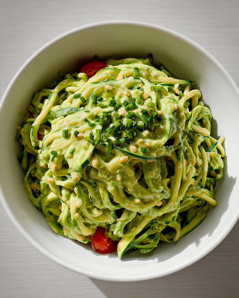 Schüssel mit Vegane Zucchini-Nudeln mit cremiger Avocado-Limetten-Sauce, garniert mit Schnittlauch.