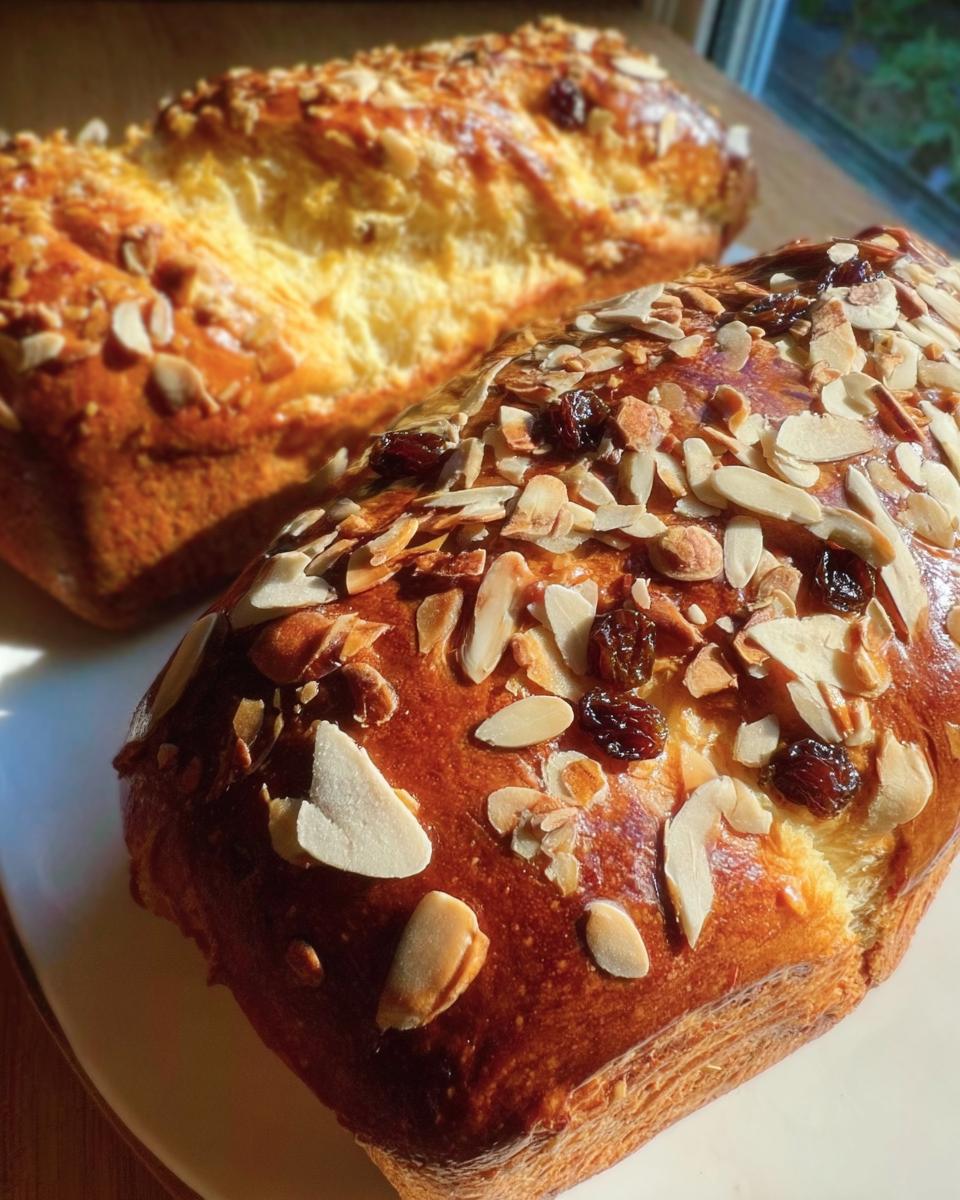 Zwei goldbraune Laibe Brioche mit Rosinen und Mandelblättchen, reichhaltig belegt.