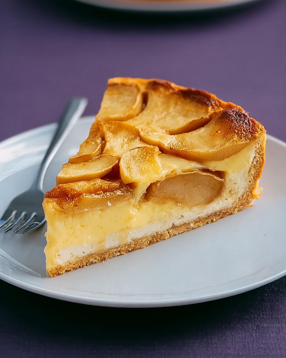 A slice of Finkenwerder Apfelkuchen with a thick custard filling and caramelized apple topping on a white plate.